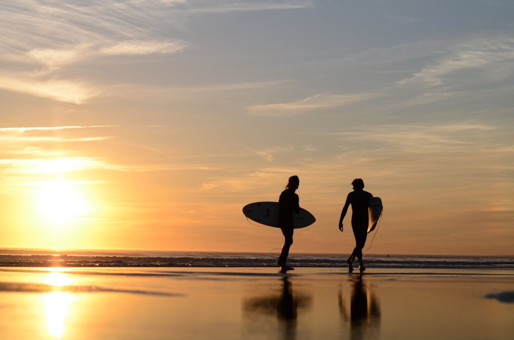 a couple of people holding surfboards on a beach