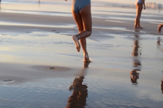 Close-up of running shoes kicking up sand during a beach sprint race at sunset.