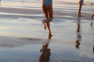 Close-up of running shoes kicking up sand during a beach sprint race at sunset.