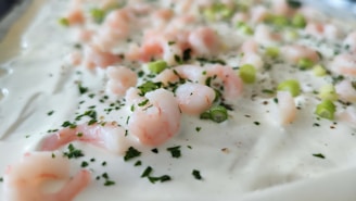 A close-up of a rich, creamy bowl of shrimp and grits topped with fresh herbs.