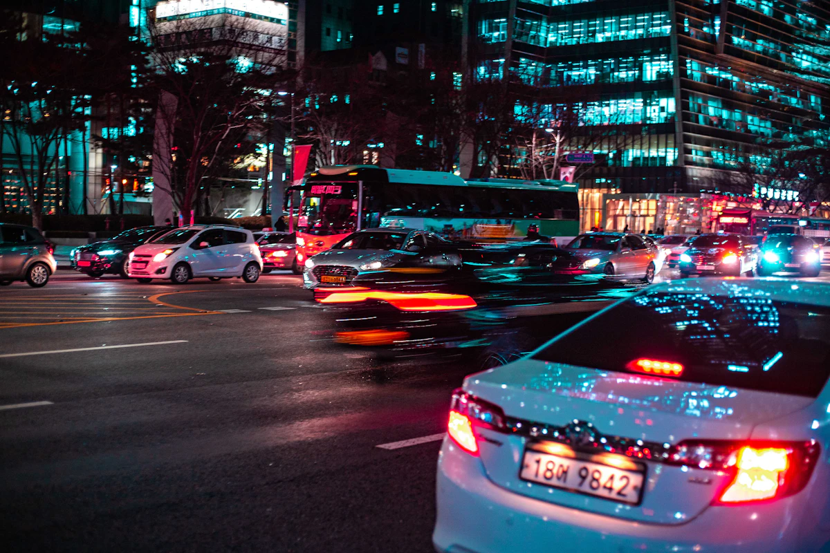 Taxis and cars streaking past lit office towers on a Seoul road at night