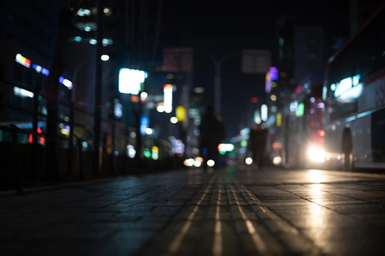A night-time city street alive with neon lights and passing silhouettes.