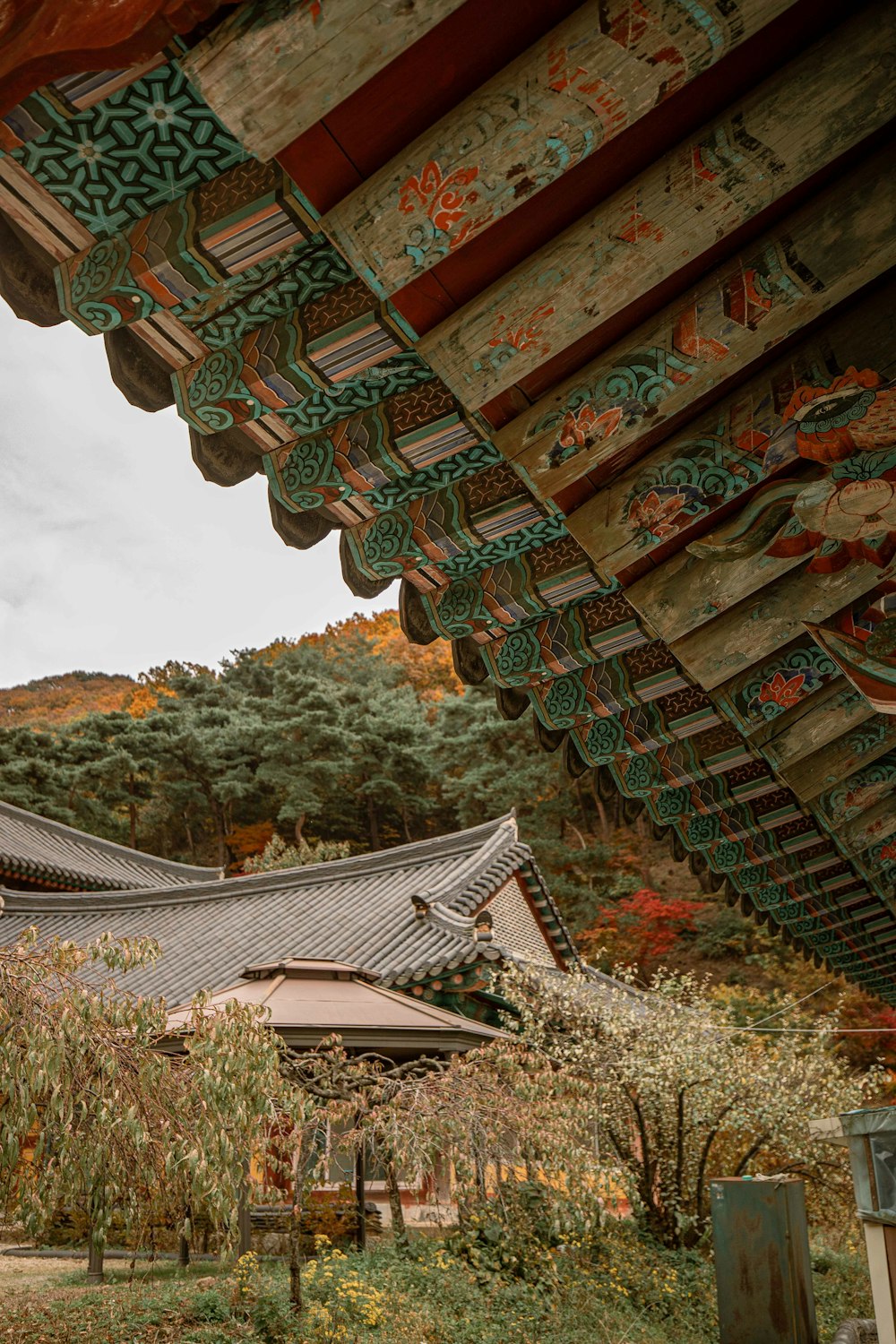 a view of a building with a roof and trees in the background