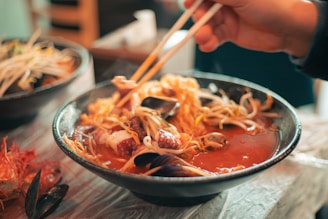 A beautifully plated bowl of steaming seafood ramen garnished with fresh herbs and vibrant vegetables.