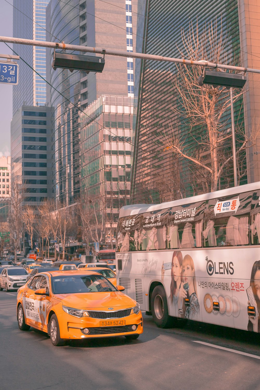 a yellow taxi cab driving down a street next to a bus