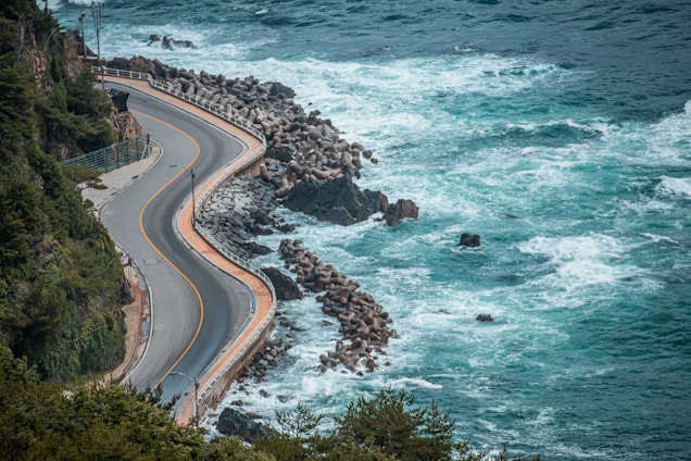 a winding road next to a body of water