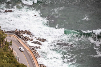 A scenic coastal road in Sri Lanka with a car driving along the ocean.