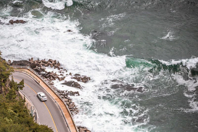 A scenic coastal road in Sri Lanka with a car driving along the ocean.