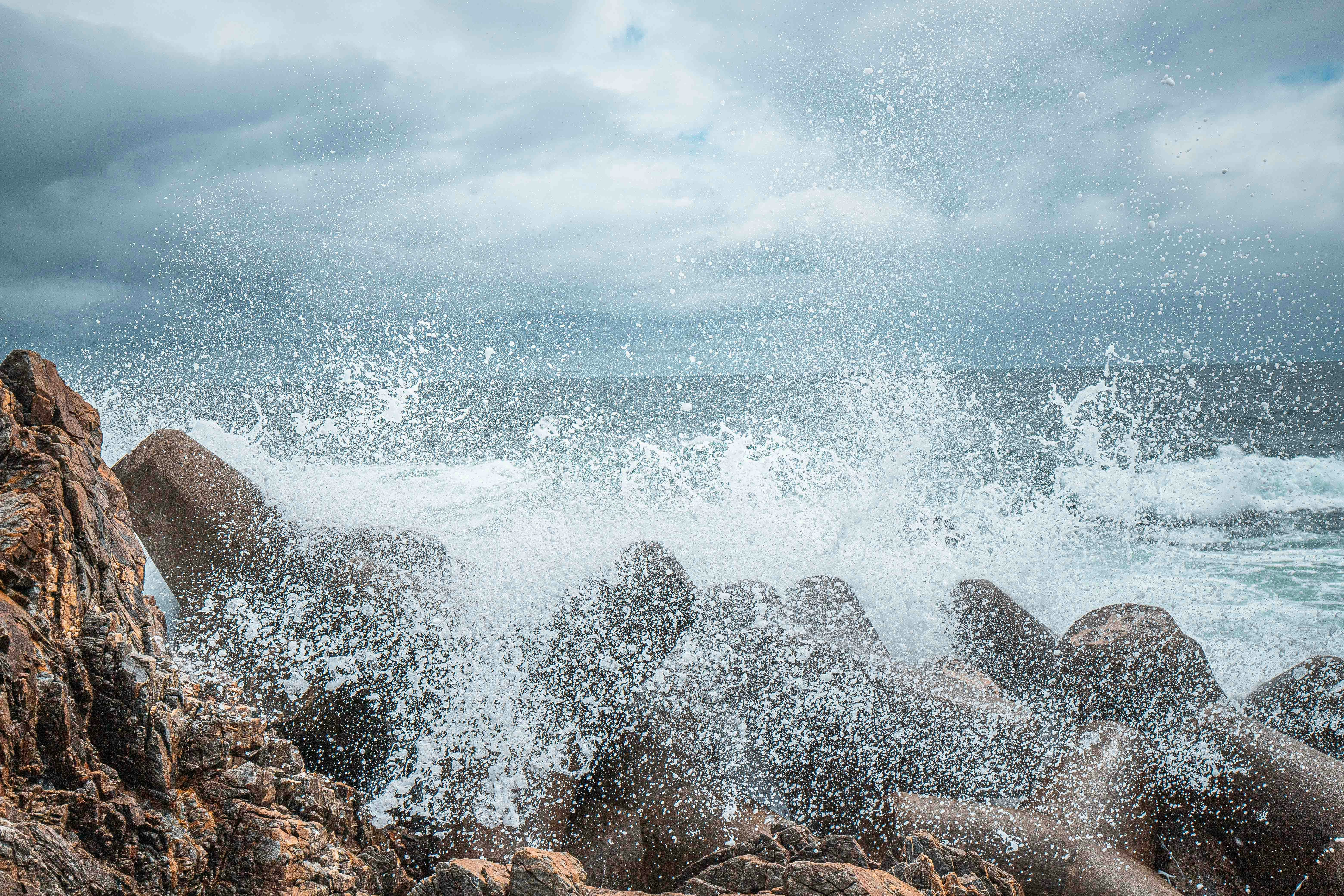a large wave hitting the rocks on the beach