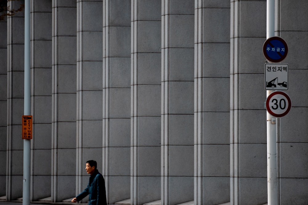 a man walking down a street next to a tall building