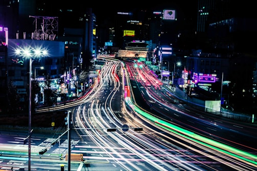 A nighttime cityscape with delivery routes highlighted in bright neon lines.