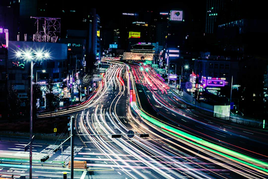 A vibrant time-lapse photo of a bustling city street glowing with neon lights.