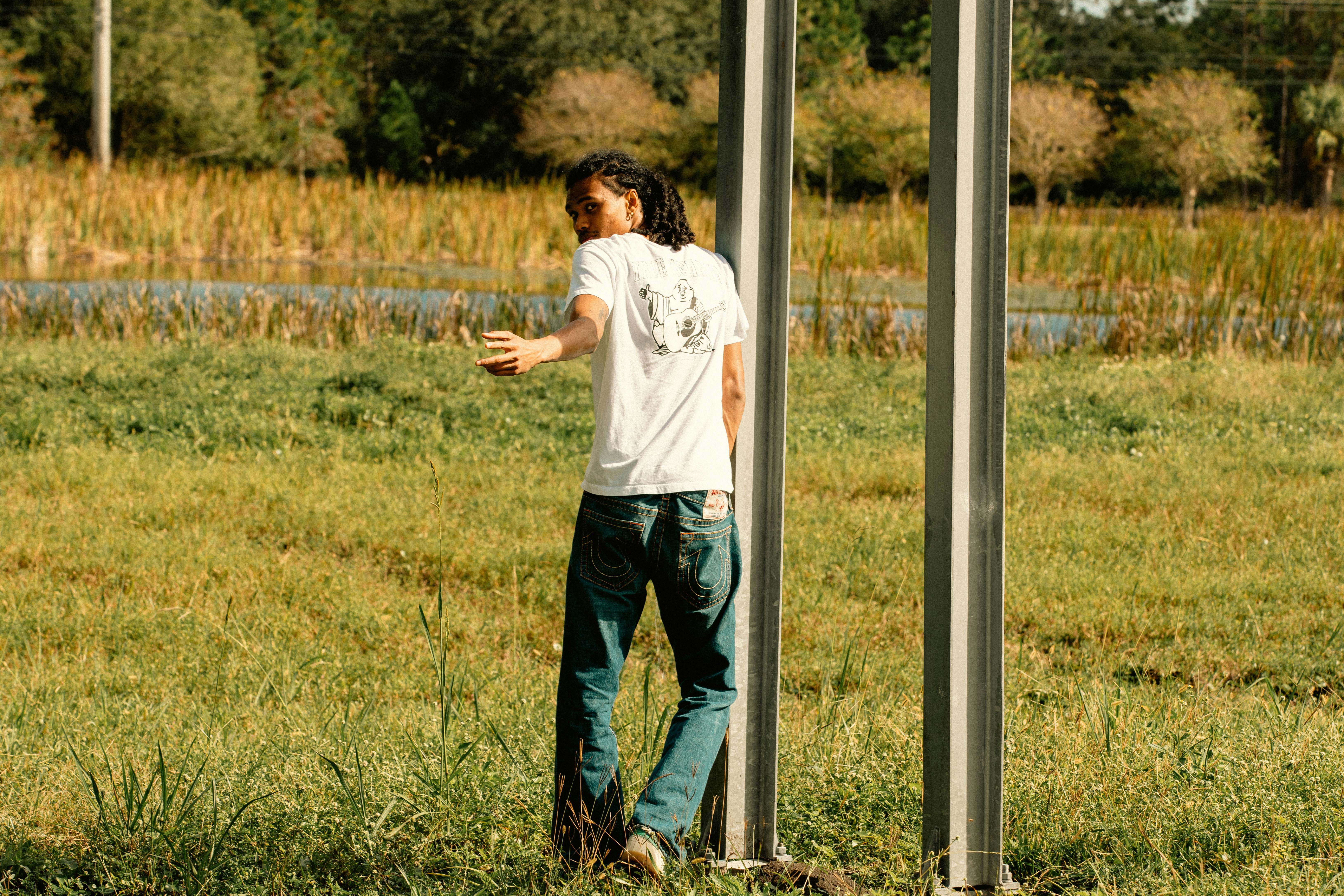 a man standing next to a pole in a field