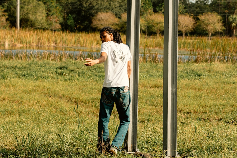 a man standing next to a pole in a field