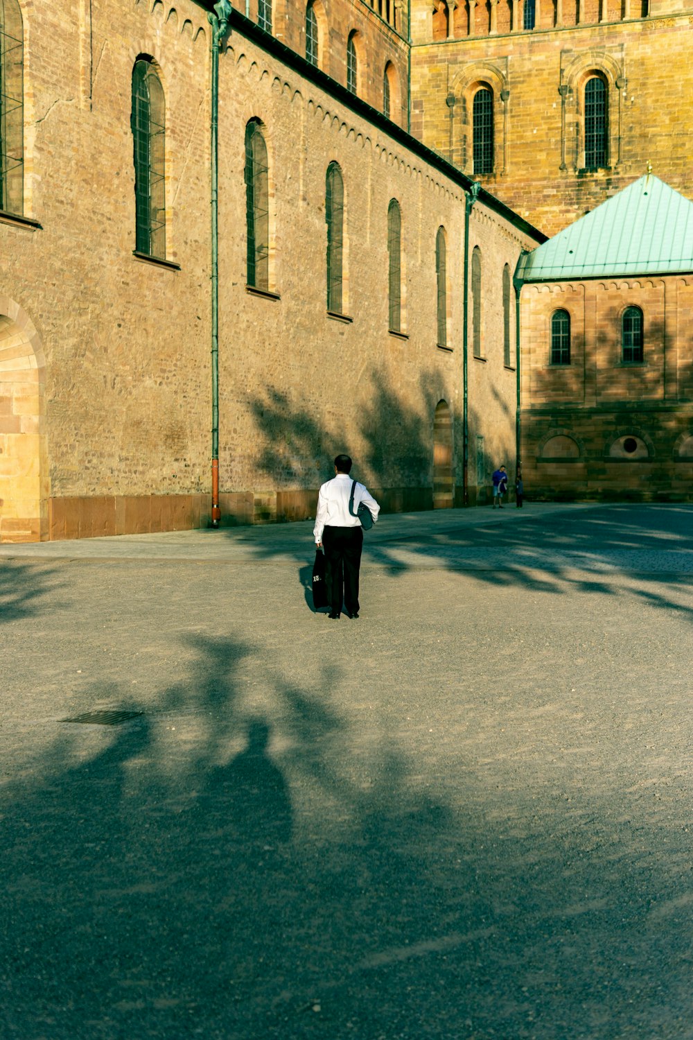 a man in a white shirt and black pants standing in front of a building