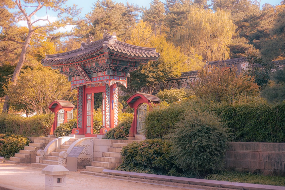 a red and white gazebo surrounded by trees and bushes