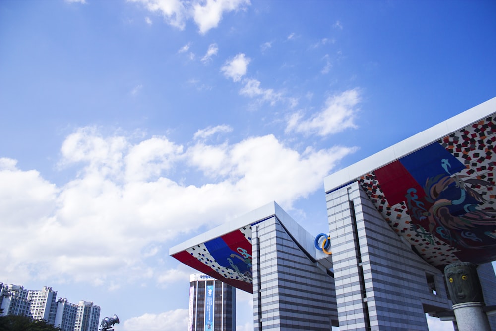 a group of flags flying in the air next to tall buildings