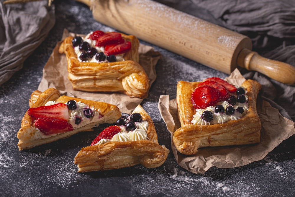 four pastries with strawberries and blueberries on them