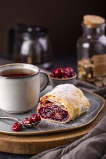 a cranberry filled pastry on a plate next to a cup of tea
