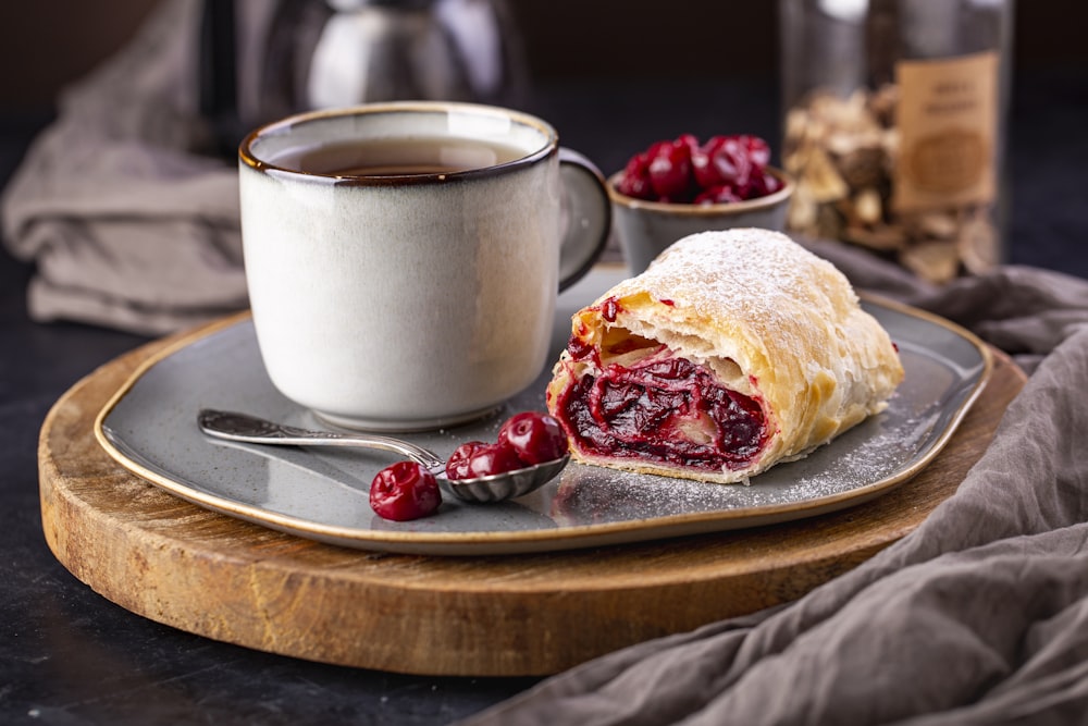 a cranberry pastry on a plate with a cup of coffee