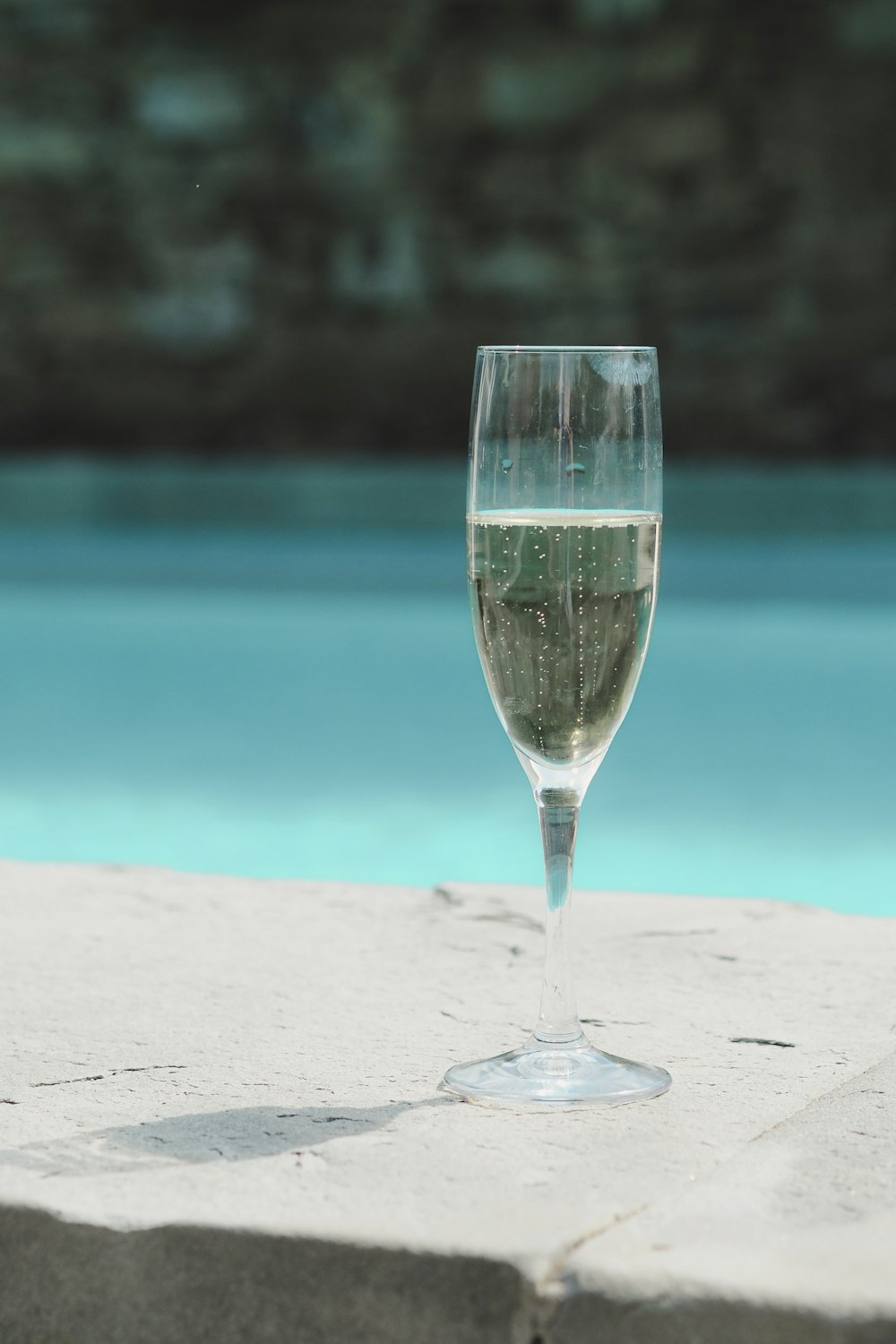 a glass of water sitting on a ledge next to a pool