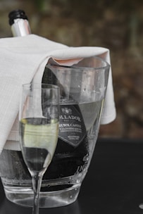 A sparkling white wine bottle chilled in an ice bucket with condensation beads.