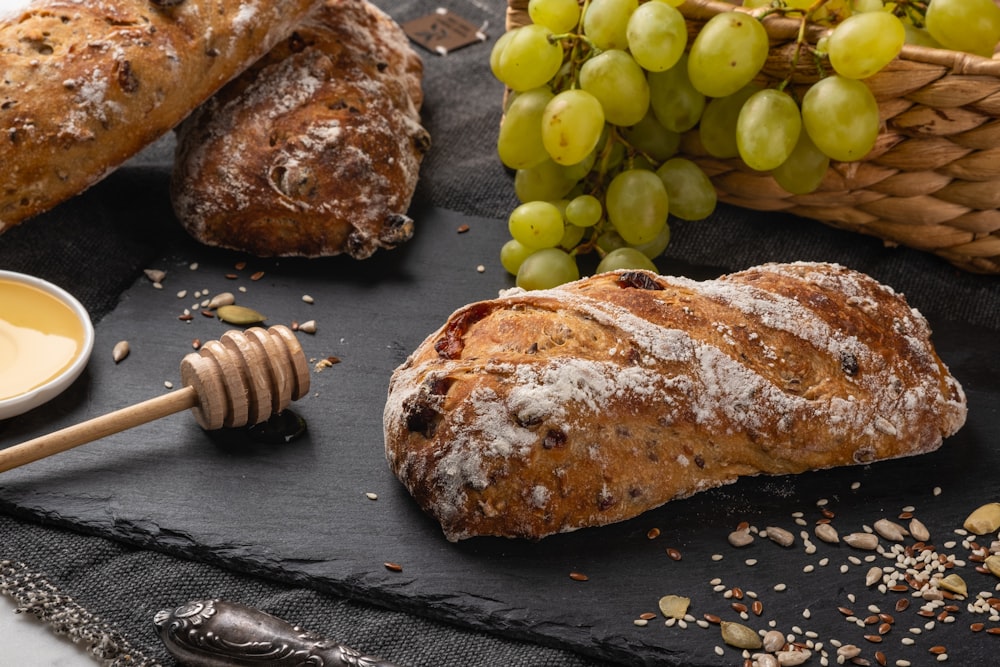 a table topped with bread and grapes next to a bowl of honey