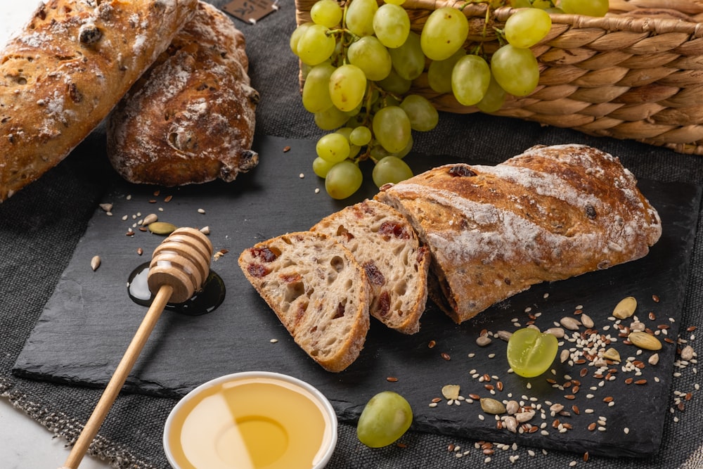 a table topped with bread and grapes next to a jar of honey