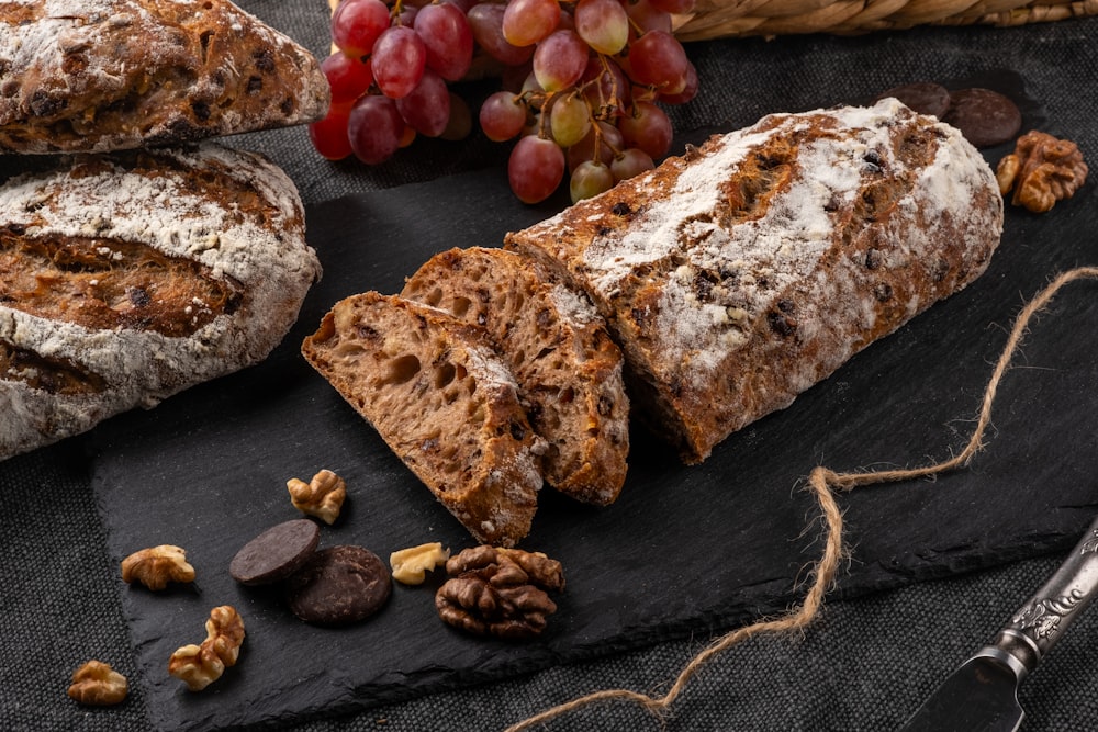 una hogaza de pan, nueces y uvas en una tabla de pizarra