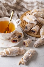 A selection of pastries displayed next to a steaming cup of chai on a rustic wooden table.
