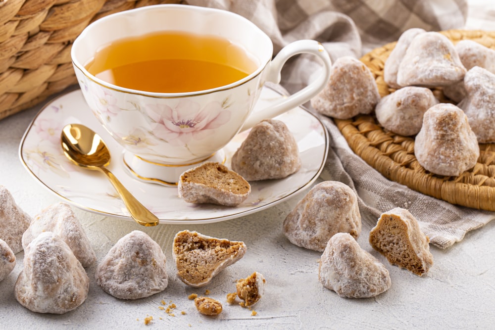 a cup of tea next to a plate of cookies