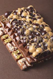 Smooth chocolate bars with visible cocoa beans and a hint of gold leaf decoration.