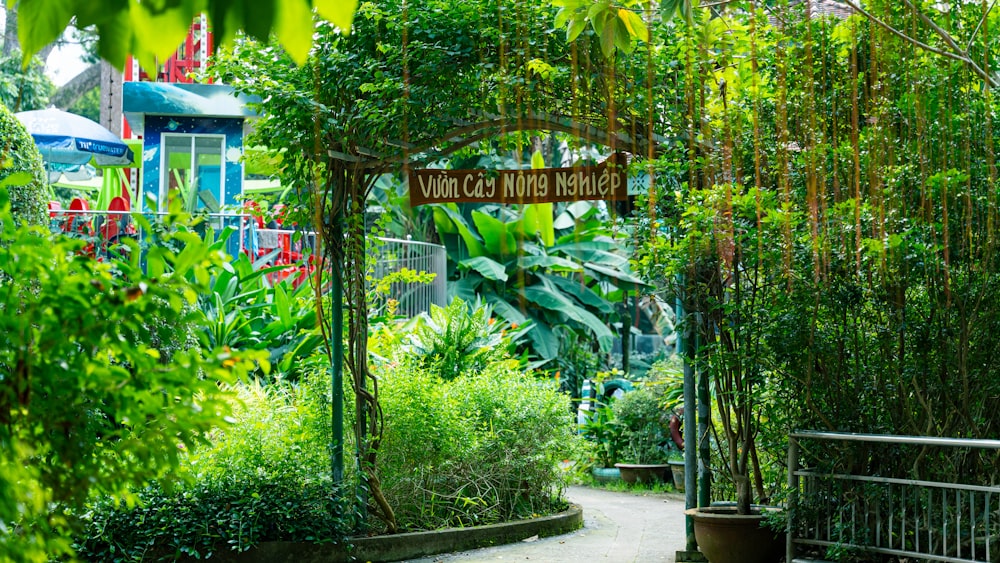 a path through a lush green garden with a wooden sign