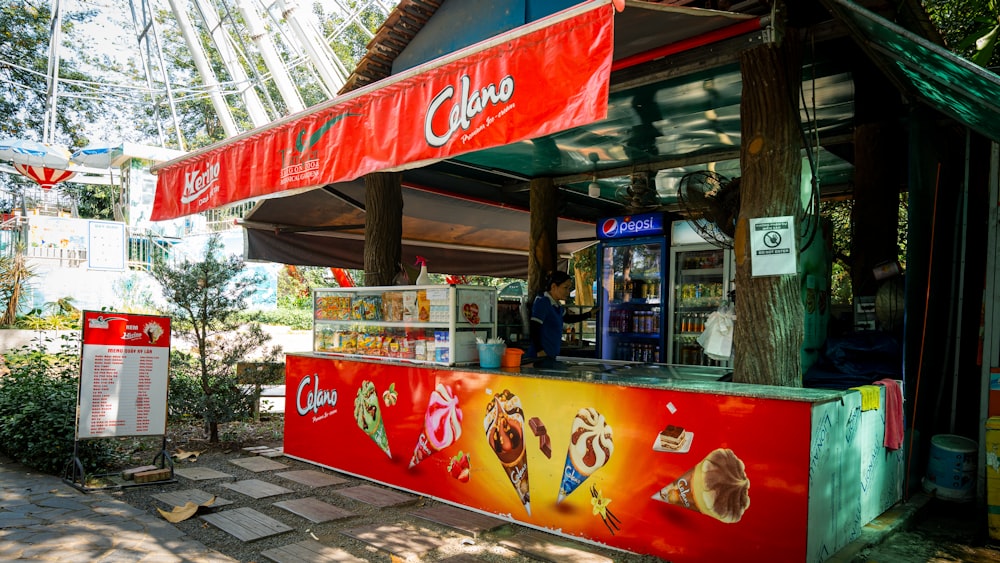 a red and yellow food stand sitting next to a forest