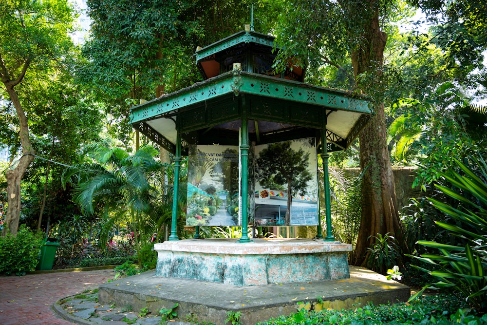 a green and white gazebo surrounded by trees