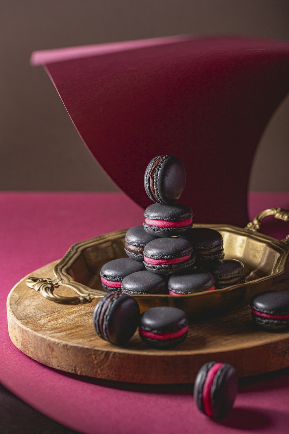 a plate of chocolate macaroons sitting on a pink chair