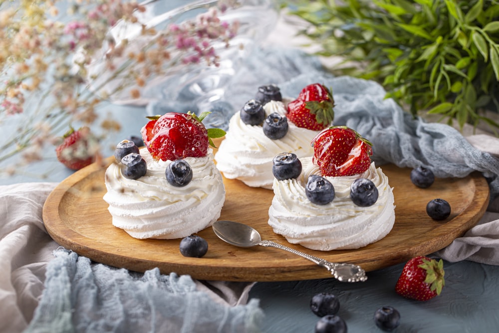 two desserts with strawberries and blueberries on a wooden platter