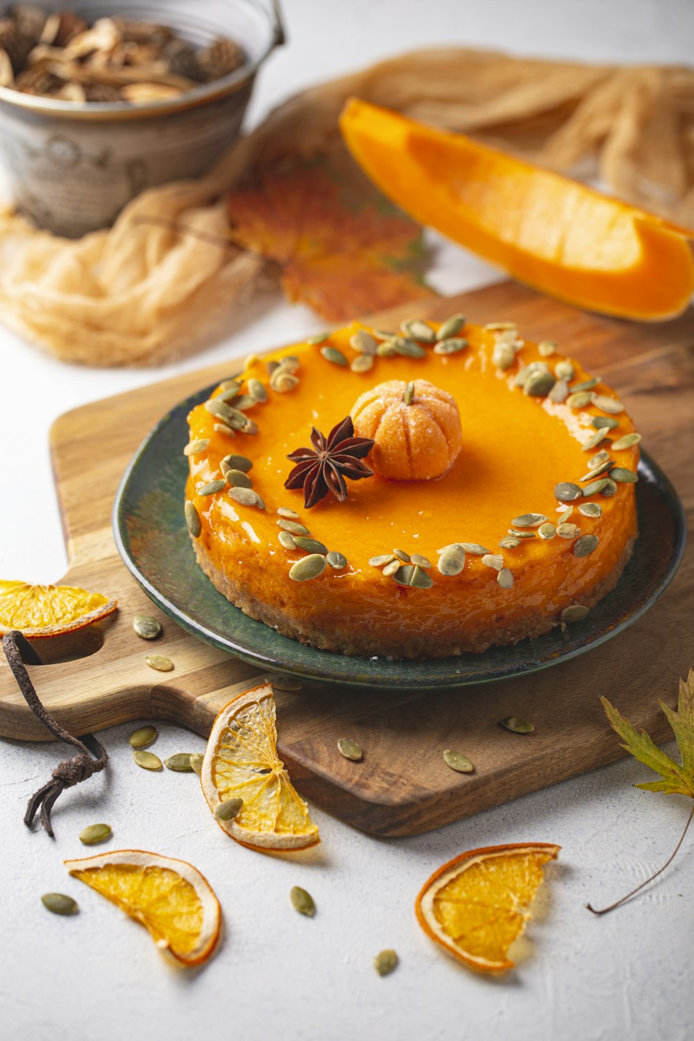 a pumpkin cheesecake on a platter surrounded by sliced oranges