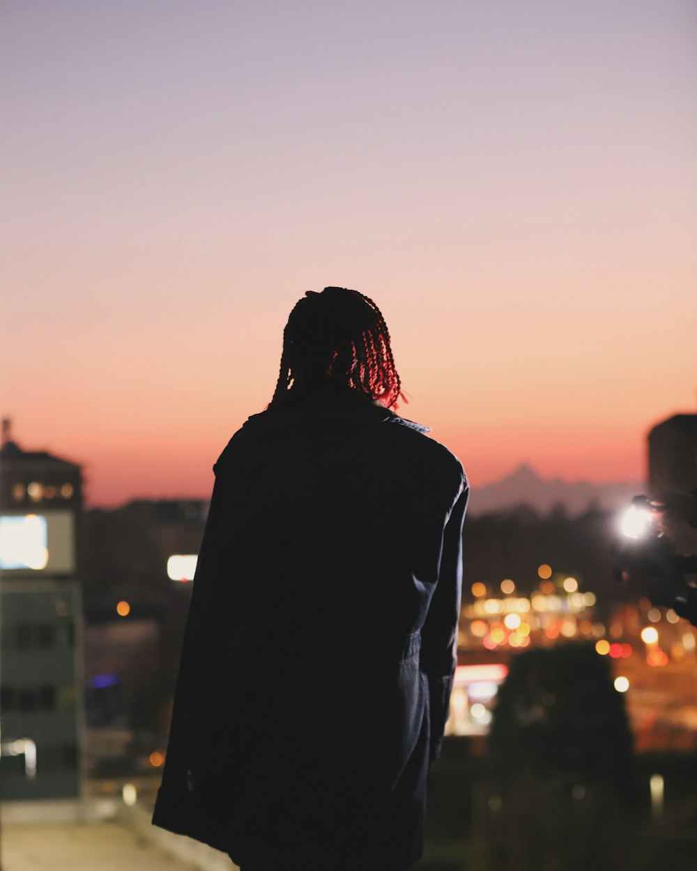 a man with dreadlocks looking out at the city