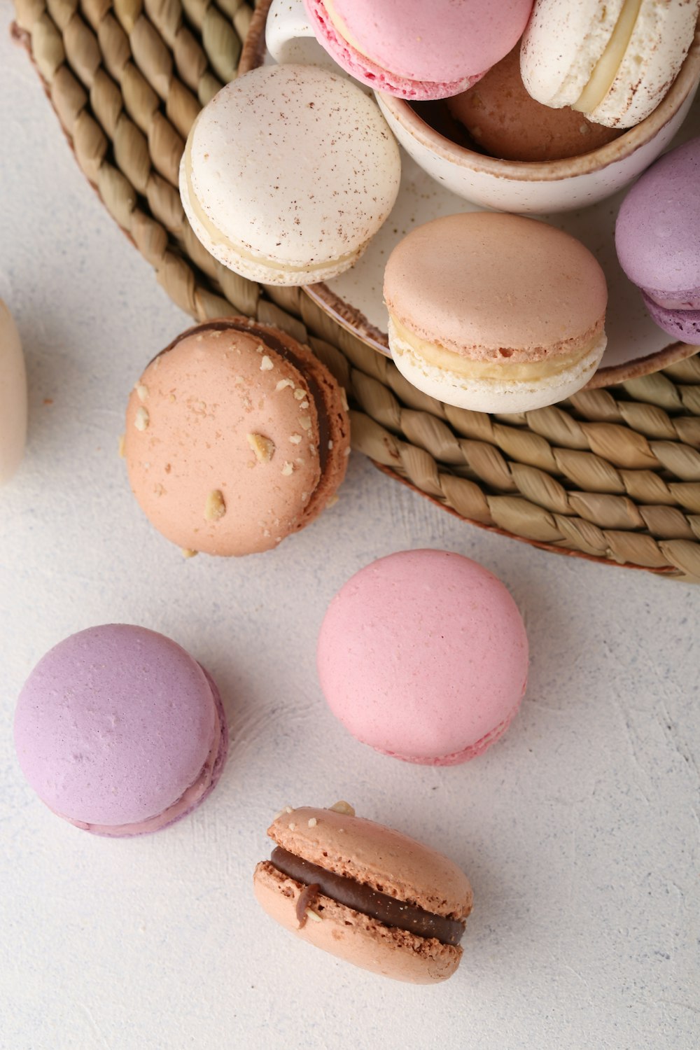 a basket filled with macaroons next to a cup of coffee