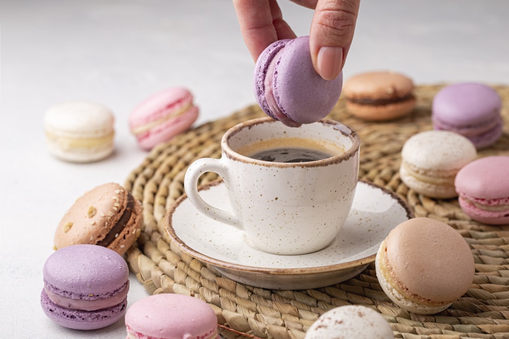 a cup of coffee and some macaroons on a wicker tray
