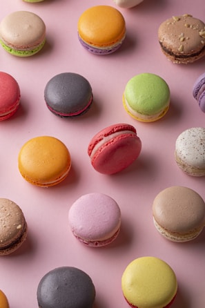 Assortment of colorful macarons arranged in a neat row on a pastel background