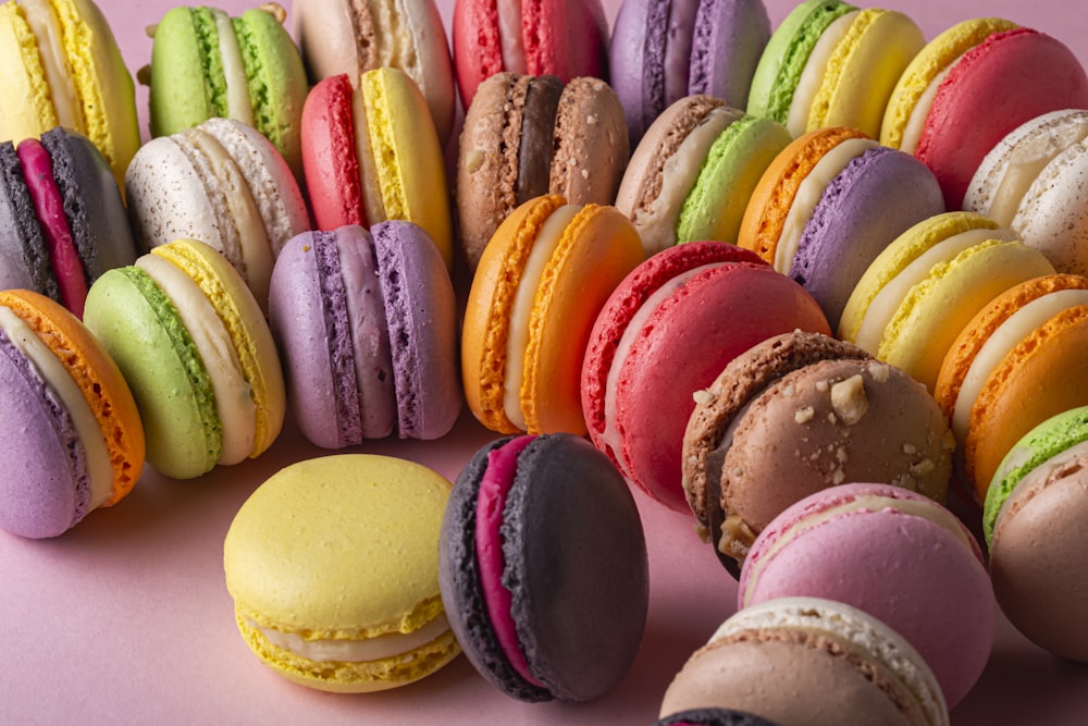 a bunch of colorful macaroons on a pink surface