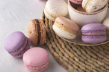 A rustic wooden table displaying a colorful assortment of macarons in pastel shades.