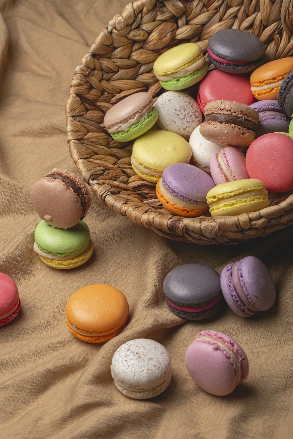 a basket full of macaroons sitting on a bed