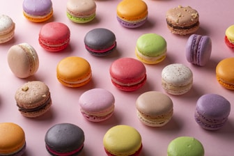a bunch of different colored macaroons on a pink surface