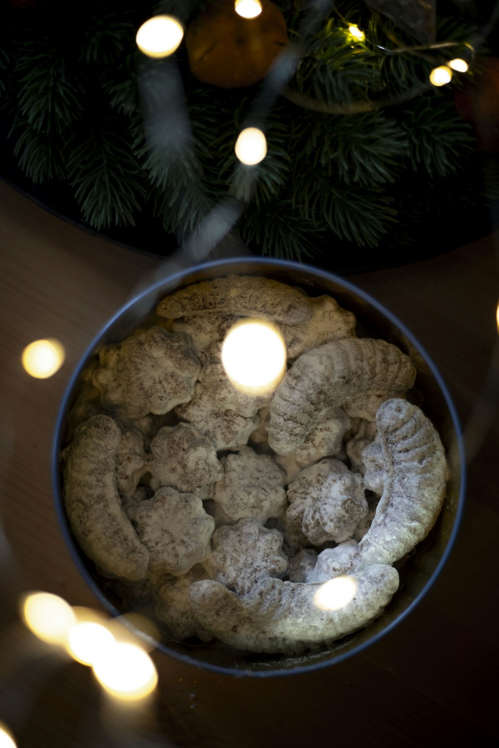 a bowl filled with cookies next to a christmas tree