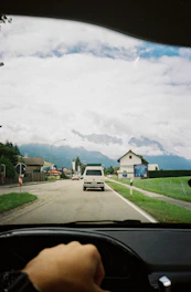 A Daihatsu car driving on a scenic road with Indonesian passengers inside.
