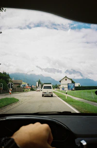 A Daihatsu car driving on a scenic road with Indonesian passengers inside.