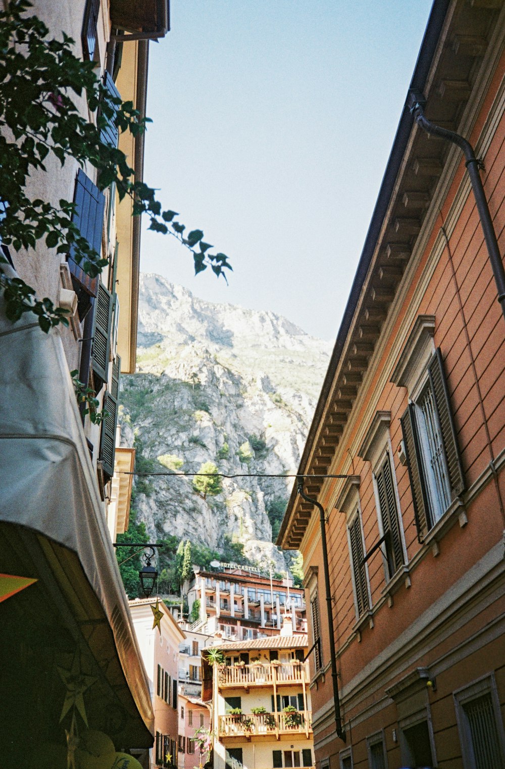 a narrow city street with a mountain in the background